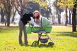 Young mother carrying baby in autumn park