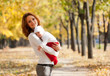 Young mother with sleeping child on hands in autumn park