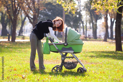 Photo: Young mother carrying baby in autumn park Young mother carrying baby in autumn park