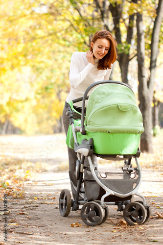 Photo: Young mother carrying baby in autumn park Young mother carrying baby in autumn park