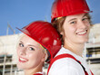 Two apprentices at work smiling in front of a building lot