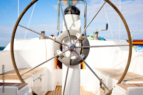 Photo: A steering wheel on a boat with empty seats. A steering wheel on a boat with empty seats.