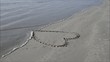 coeur de sable effacé par une vague