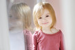 Adorable smiling little girl by the window