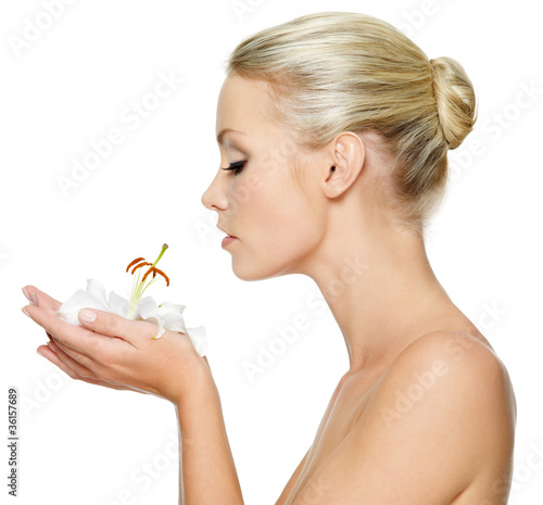 Photo: Beautiful young woman holding a white lily at face Beautiful young woman holding a white lily at face