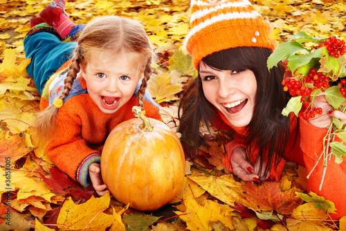 Photo: Happy family with pumpkin on autumn leaves. Happy family with pumpkin on autumn leaves.