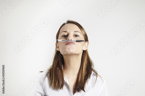 Photo: young businesswoman holding pen with his nose young businesswoman holding pen with his nose