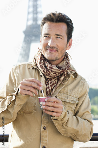 Photo: Man holding a disposable cup with the Eiffel Tower in the background, Paris, Ile-de-France, France Man holding a disposable cup with the Eiffel Tower in the background, Paris, Ile-de-France, France