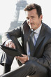 Photo: Businessman using a digital tablet with the Eiffel Tower in the background, Paris, Ile-de-France, France Businessman using a digital tablet with the Eiffel Tower in the background, Paris, Ile-de-France, France