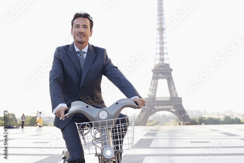 Photo: Businessman riding a bicycle with the Eiffel Tower in the background, Paris, Ile-de-France, France Businessman riding a bicycle with the Eiffel Tower in the background, Paris, Ile-de-France, France
