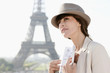 Foto: Woman holding a guide book with the Eiffel Tower in the background, Paris, Ile-de-France, France Woman holding a guide book with the Eiffel Tower in the background, Paris, Ile-de-France, France