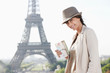 Photo: Woman holding a postcard with the Eiffel Tower in the background, Paris, Ile-de-France, France Woman holding a postcard with the Eiffel Tower in the background, Paris, Ile-de-France, France