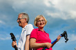 Happy mature or senior couple doing Nordic walking in summer