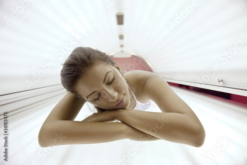 Photo: Beautiful young woman tanning in solarium Beautiful young woman tanning in solarium
