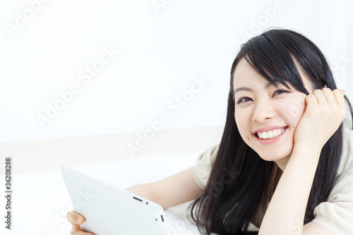 Photo: ベッドでタブレットPCを使う女性 ベッドでタブレットPCを使う女性