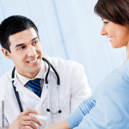 Foto: Happy doctor giving an injection to female patient Happy doctor giving an injection to female patient