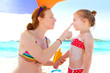 daughter and mother in beach with sunscreen
