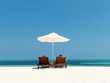 Couple in chairs resting on the beach near sea