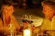 Caucasian couple smiling and toasting wine glasses in restaurant