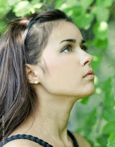 Photo: Portrait of beautiful cute young girl yearning in leafage outdoo Portrait of beautiful cute young girl yearning in leafage outdoo