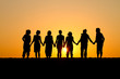 silhouette of group of friends standing in sunset at beach silhouette of group of friends standing in sunset at beach