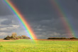 Natural two rainbow over green field and dark sky Natural two rainbow over green field and dark sky