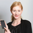 Junge, lächelnde Frau präsentiert ihr Smartphone