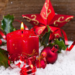 candle,holly,baubles,star and ribbons in snow before wood