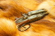Old hunting gun on red fox fur background