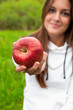 Photo: Young girl showing a red apple outdoors Young girl showing a red apple outdoors