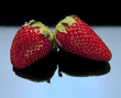 Two strawberries with black reflection.