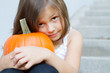 little, caucasian girl holding pumpkin in her hands