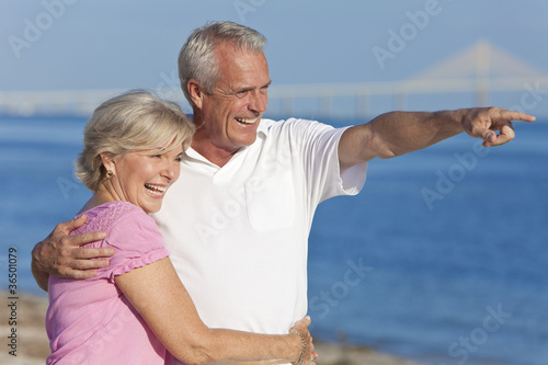 Photo: Happy Senior Couple Walking Pointing on Beach Happy Senior Couple Walking Pointing on Beach