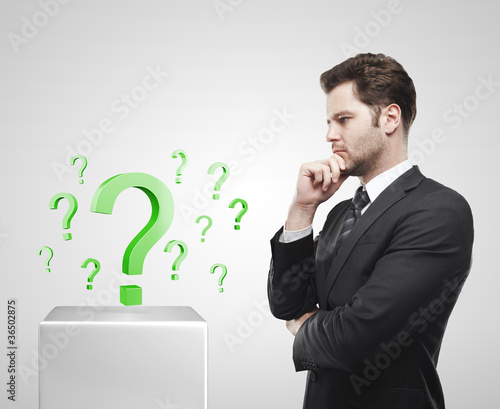 Photo: Young businessman look at the green question marks Young businessman look at the green question marks