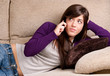 Photo: Young girl concerned talking by telephone bad news lying on sofa Young girl concerned talking by telephone bad news lying on sofa