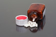 Pills and bottle on reflective surface