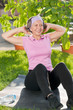 Senior sportive woman doing sit-ups sunny day