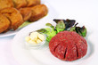 Steak tartare with garlic on white plate with onions and toast