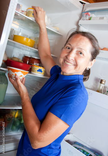 Photo: Ordinary woman taking something of the fridge Ordinary woman taking something of the fridge