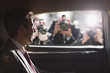 Politician smiling for paparazzi in backseat of car