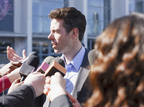 Photo: Politician talking into reporters' microphones Politician talking into reporters' microphones