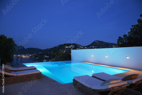 Photo: Pool with lounge chairs at night Pool with lounge chairs at night