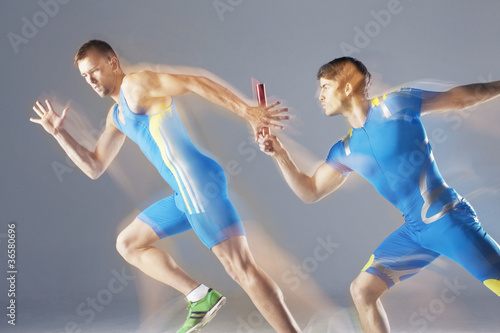 Photo: Blurred view of athletes passing baton Blurred view of athletes passing baton