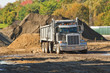 A dump truck about to unload a pile of dirt
