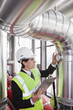 Businessman checking gauges on pipes in factory