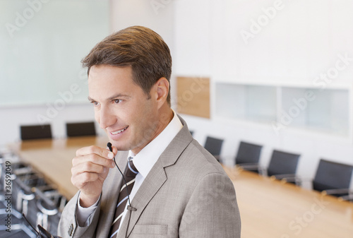 Photo: Businessman speaking into microphone in conference room Businessman speaking into microphone in conference room