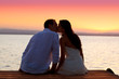Foto: couple kissing at sunset sitting in jetty couple kissing at sunset sitting in jetty