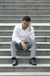 Asian businessman sitting steps holding his head 