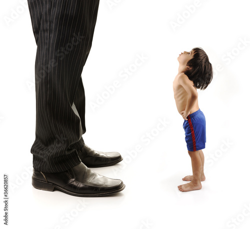 Photo: Little small child is looking at the giant legs of businessman Little small child is looking at the giant legs of businessman