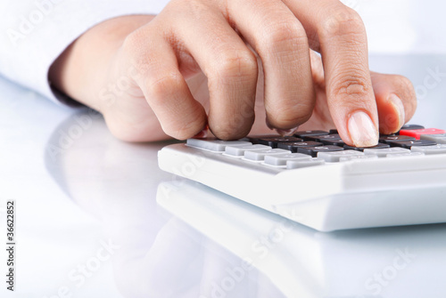Photo: hand using calculator on white hand using calculator on white